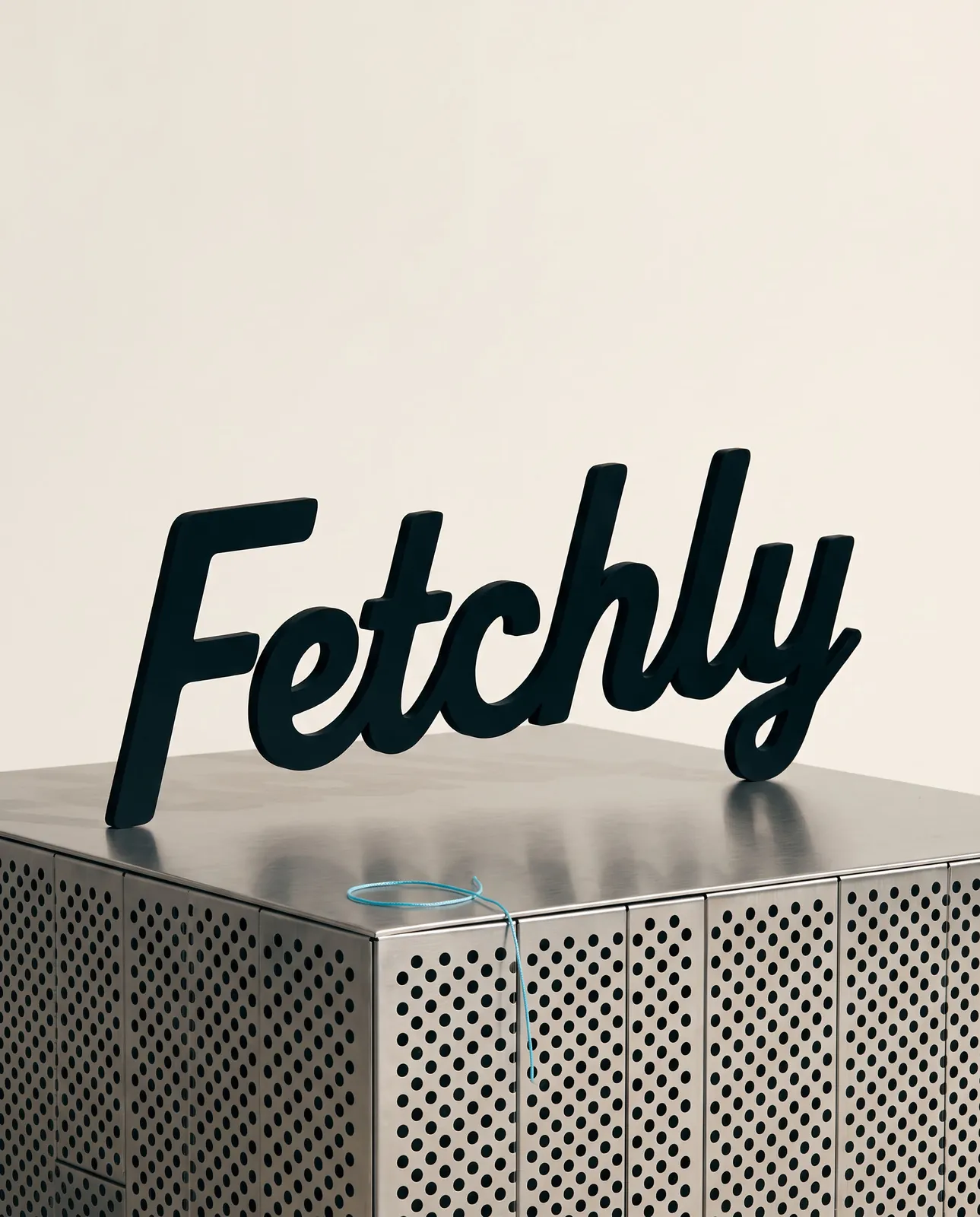 The Fetchly script wordmark standing on a perforated steel plinth